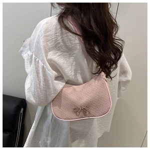 Detailed view of pink corduroy shoulder bag with gold bow clasp on female model