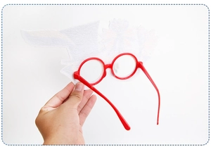 Detail of red party glasses featuring white flame felt feathers for Carnival festivities