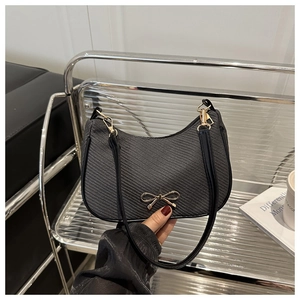 Detail of black baguette bag with bow hardware and textured twill surface