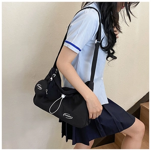 Details einer großen schwarzen Nylon-Beuteltasche mit Kordelzug und kleiner runder Geldbörse