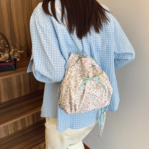 Minimalist white floral drawstring backpack with blue plaid straps and bow decoration