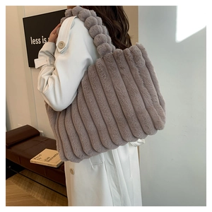Detail of grey-purple plush tote bag with vertical stripes and fluffy ball handle