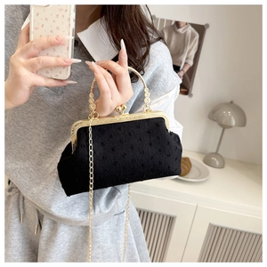 Detail of black fabric square bag with gold filigree handles and fine dot texture
