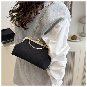 Retro black kiss-lock bag with 3D dot texture and gold chain on model in home setting