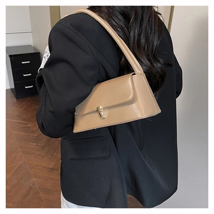 Close-up of khaki underarm bag with gold metal buckle worn with a black office blazer