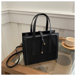 Close-up of a black matte leather tote bag with elegant golden accents and shoulder strap