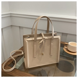 Detail of cream faux leather handbag with accordion pleats and metal buckle accents