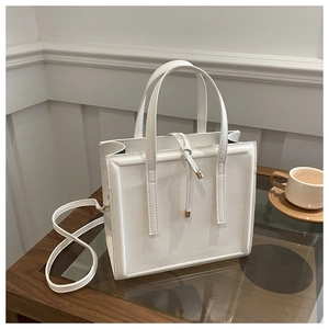 Macro view of white square faux leather bag with fine texture and gold hardware detail