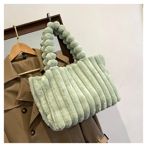 Detail of mint green plush tote bag with quilted texture and decorative ball handle