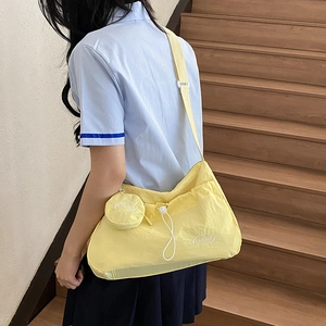 Minimalist light yellow nylon crossbody bag with matching round coin purse on a model