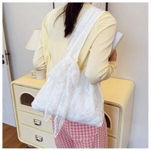 Detailed close-up of a white lace tote bag with floral embroidery and ribbon accents
