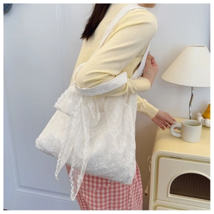 Detailed side view of white lace tote bag with floral embroidery and bow decoration