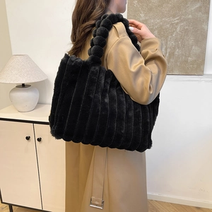 Black plush tote bag with vertical stripes and unique bubble handles shown on model