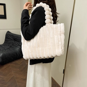 Chic beige plush tote bag with unique furry pom-pom handle shown in a modern interior