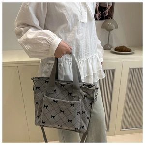 Dettaglio borsa tote in velluto a coste grigio con fiocchi neri in interno moderno