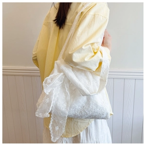 Lace shoulder bag with oversized bow detail and delicate floral embroidery textures