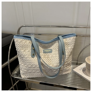 Detail of crochet tote bag featuring light blue leather trim and fashion logo branding