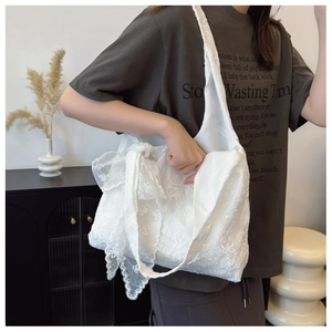 Detail of white lace tote bag featuring exquisite embroidery and a large decorative bow