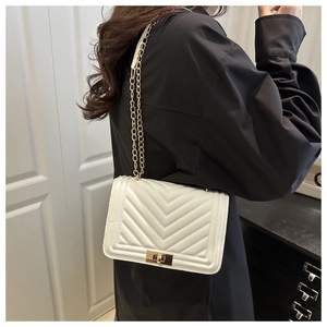 Detail of white leather shoulder bag with chevron quilting and golden chain strap