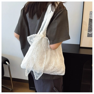 Detail of white floral lace tote bag featuring a large decorative bow and elegant texture
