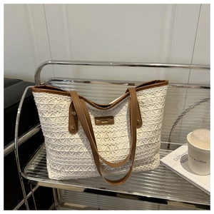 Detail of crochet lace tote bag with brown leather handles and brand logo tag