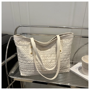 Detail of hollow star crochet texture and leather logo on beige woven tote bag