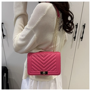 Detailed view of rose red quilted chain bag with gold lock worn by model on shoulder