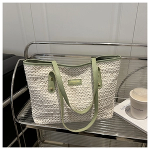 Detailed close-up of white floral lace tote bag with light green straps on a metal shelf