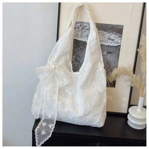 Detailed close-up of intricate white lace embroidery and large bow on a tote bag