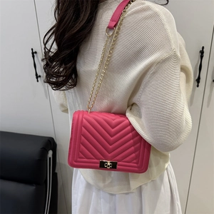 Magenta quilted crossbody bag with gold chain strap shown from a back side view