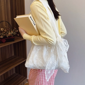 White lace tote bag with embroidery and large bow detail shown in a lifestyle setting