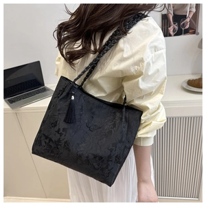 Detail of black tote bag with butterfly jacquard embroidery and tassel pendant accessory