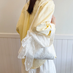 Lace flower canvas tote bag with side bow detail shown on model against white wood wall