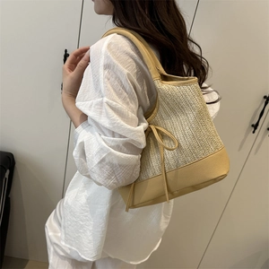 Large straw beach tote bag with yellow leather trim and straps worn by model