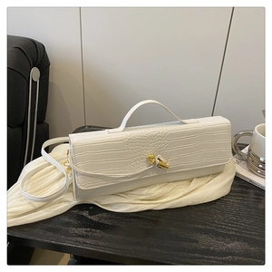Detail of white crocodile embossed baguette bag with elegant golden knot buckle closure