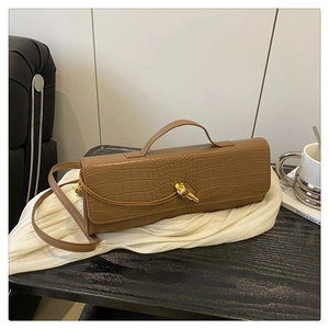 Detailed view of brown crocodile texture on baguette bag with golden knot clasp