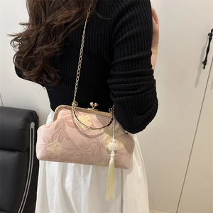 Pink vintage kiss-lock shoulder bag with gold floral patterns and a white tassel