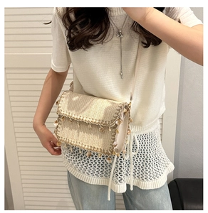 Dettaglio della borsa a spalla in paglia con eleganti frange beige e decoro di paillettes