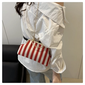 Sac bandoulière rayé rouge et blanc avec cadre doré et bandoulière chaîne sur modèle