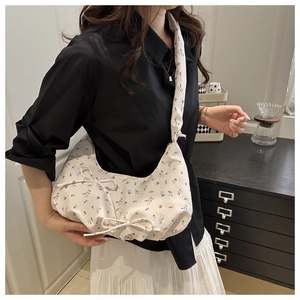 Floral canvas crescent bag worn by model featuring bow details and a pleated cloud design