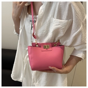 Détail du sac bandoulière rose vif avec texture cuir litchi et fermoir doré rotatif
