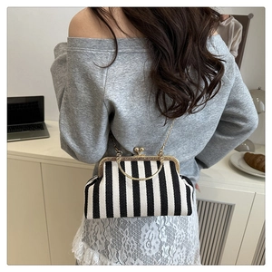 Détail du sac à main vintage à rayures verticales avec poignée anneau dorée et chaîne
