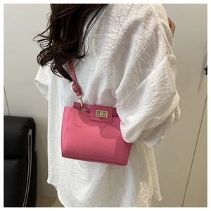 Sac bandoulière rose texture grainée avec fermoir tournant doré en situation réelle