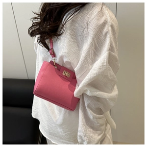 Détail du sac à bandoulière rose à grain de litchi avec fermoir doré sur tenue blanche