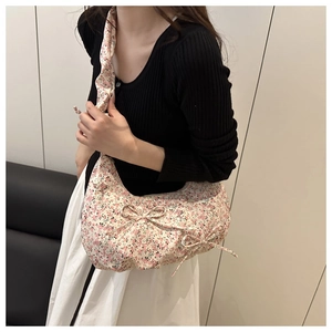 Detail view of floral pleated shoulder bag with pink bow accent and soft fabric texture