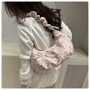 Detail view of floral pleated shoulder bag with dual bow accents and ruched cloud strap