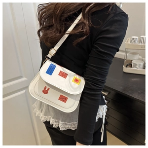 Close-up of white crossbody bag with colorful patches worn by a model in a minimal setting