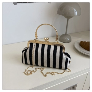 Gros plan du sac tissé à rayures noires et blanches avec poignée dorée et bandoulière