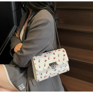 Détail du sac bandoulière blanc à imprimé cerise et chaîne argentée sur modèle