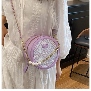 Detail view of round purple crossbody bag with pearl charms and gold chain strap